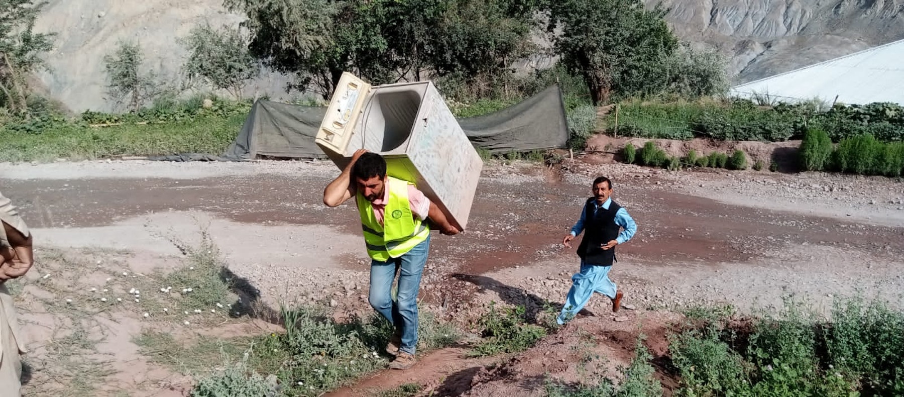 A CERT volunteer helping to carry the belongings of a family evacuating their at-risk home in Sherqilla