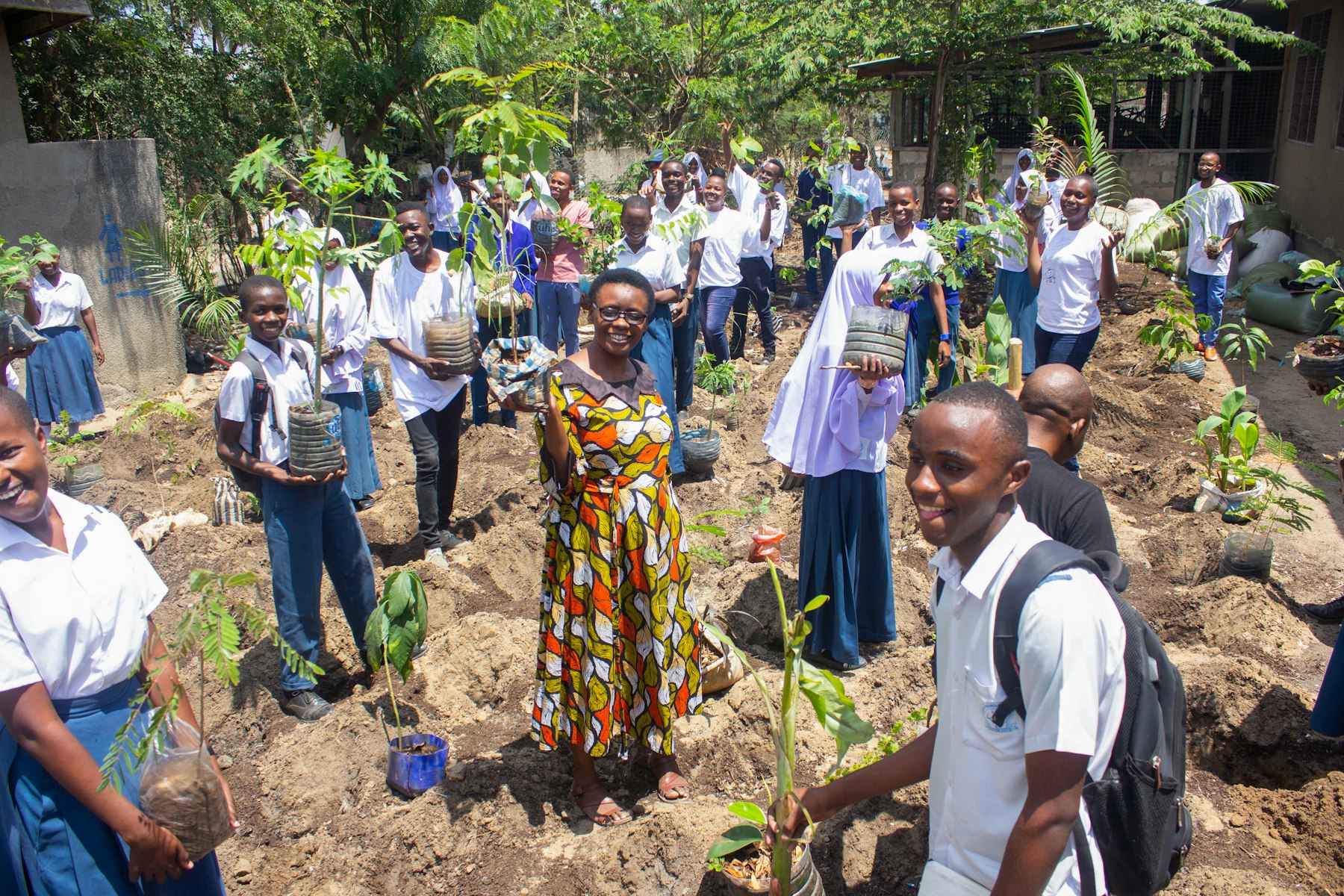 Vailet Semwaiko (centre), teacher at Mbande Secondary School in Dar es Salaam, leads students and volunteer parents in planting micro-forests.
