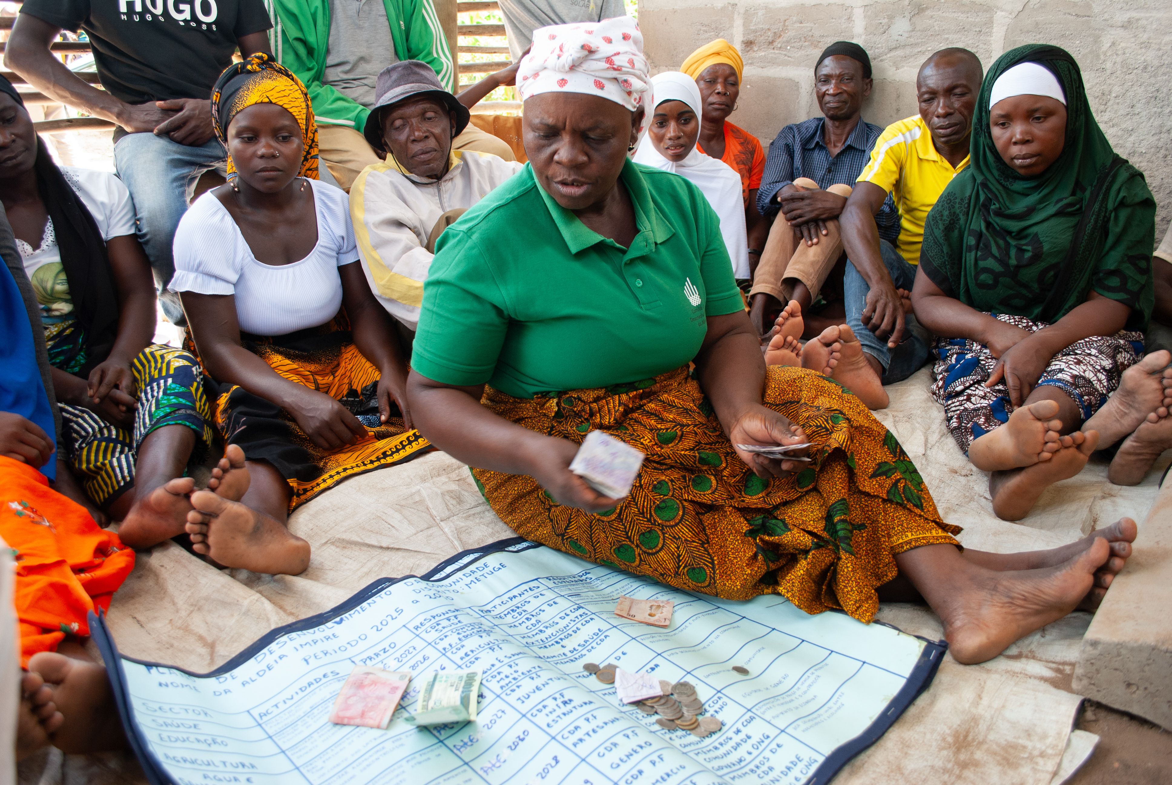 A community leader counts savings during a village savings group meeting in Mozambique